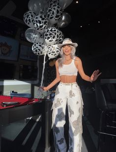 a woman standing in front of a table with many balloons on top of her head