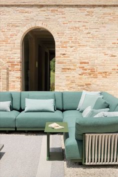 a blue couch sitting in front of a brick wall next to a green coffee table