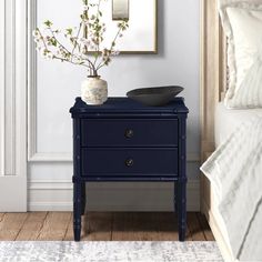 a blue nightstand with flowers on it next to a bed