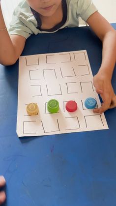 a young boy is playing with some sort of game on the table in front of him