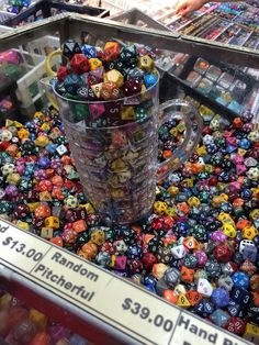 a large cup filled with lots of different colored dice next to a pile of other colorful dice