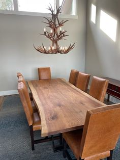 a dining room table with chairs and a deer antler chandelier hanging from the ceiling