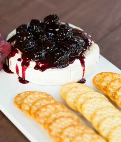 grapes and crackers on a white plate with blueberry cheese dip in the middle