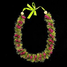 a green and pink flowered necklace with a bow on it's neckline