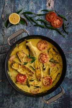 a pan filled with chicken and tomatoes on top of a blue table next to green beans