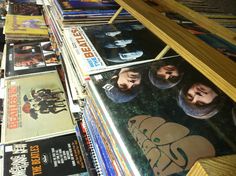 the beatles album covers are on display in a record store's shelves, and they are lined up against each other