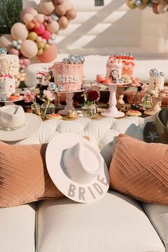 a white hat sitting on top of a couch next to pillows and cake covered in frosting