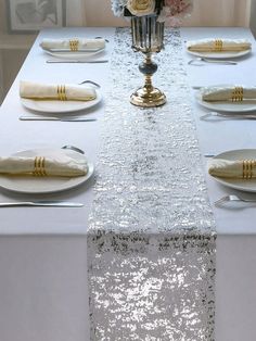 the table is set with white and gold place settings