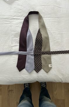 three ties laid out on top of a bed with one tied up to the side