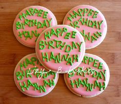 four decorated cookies with green icing on a wooden table next to the words happy birthday