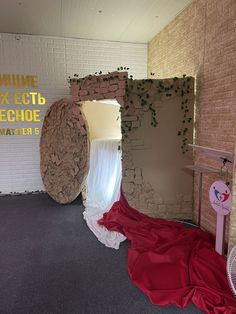 an empty room with a red sheet on the floor and a brick wall behind it