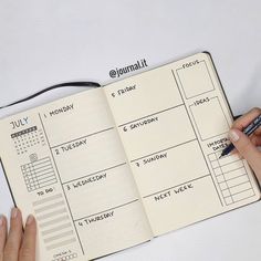 a person is writing on a planner with a pen in their hand and holding a notebook