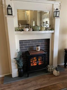 a fireplace with a mirror above it next to a table and potted plants on the mantle