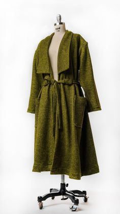 a green coat is hanging on a mannequin