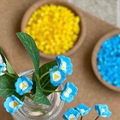 blue and yellow flowers are in small vases on the table next to each other