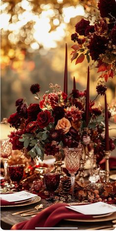 the table is set with red flowers and gold place settings for an elegant dinner party