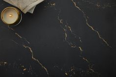 a candle and some towels on a black counter top with gold trimmings in front of it