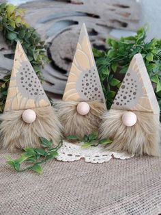 three little gnome hats sitting on top of a table next to some greenery and a lace doily