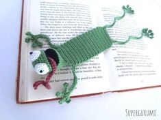 a crocheted gecko laying on top of an open book