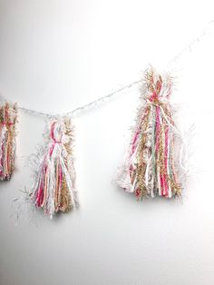 three tassels hanging from a string on a white wall with pink and gold trim