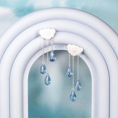 Indulge in the charming whimsy and elegance of these Cloud and Rain Drop Dangle Earrings. The delicate chains with blue teardrop crystals elegantly dangle like rain drops, while the satin finish on the cloud adds a unique texture that will surely catch the eye. Crafted with solid 925 sterling silver, these earrings are not only gorgeous but also of high quality. Perfect for those who love to match their accessories to the ever-changing weather! Sold as a pairMaterials: 925 sterling silver, resin Drop Dangle Earrings, 925 Sterling Silver Chain, The Cloud, Rain Drops, Solid 925 Sterling Silver, Satin Finish, Sterling Silver Chains, Dangle Drop Earrings, Dangle Earrings