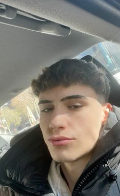 a young man sitting in the back seat of a car