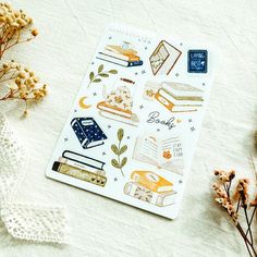 a sheet of paper with some books on it and flowers in the foreground next to it