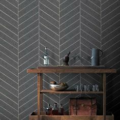 a shelf with bottles and glasses on it in front of a chevron wallpaper