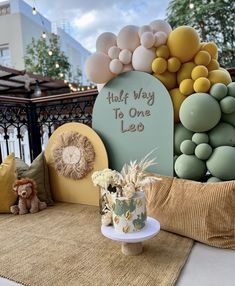 a table topped with balloons and stuffed animals next to a sign that says half way to one leo