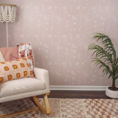 a white rocking chair in front of a pink wallpapered room with a potted plant