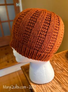 an orange knitted hat sitting on top of a white mannequin head