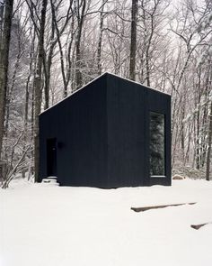 a black cabin in the middle of a snowy forest