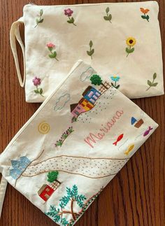 two small pouches with embroidered designs on them sitting on top of a wooden table