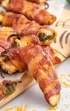 bacon wrapped jalapenos sitting on top of a cutting board next to other food items