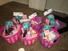 several pink baskets filled with personal care items on the floor next to a black suitcase