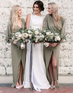 three bridesmaids standing together with their bouquets in front of a brick wall