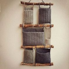 a wall hanging made out of knitted material and wooden pegs with two bags on it