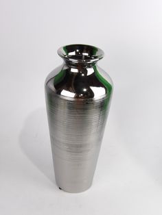 a shiny silver vase with green accents on the top and bottom is sitting against a white background