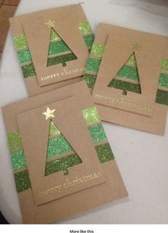 three brown christmas cards with green glitter trees on them, sitting on a white table