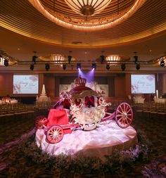 an elaborately decorated horse drawn carriage sits in the middle of a banquet hall with chairs and tables