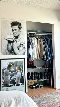 a bedroom with pictures on the wall and an open closet in front of it that is filled with clothes