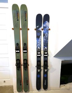 three skis and one snowboard are hanging on the wall next to each other