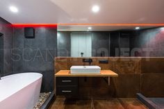 a bathroom with a large white bath tub sitting next to a wooden counter top under a red light