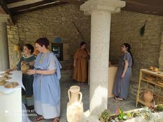 three women in ancient greek dress are talking to each other while another woman looks on