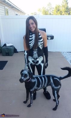 a woman in skeleton costume standing next to a dog