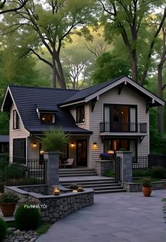 a large house with lots of windows and lights on the front porch, surrounded by trees