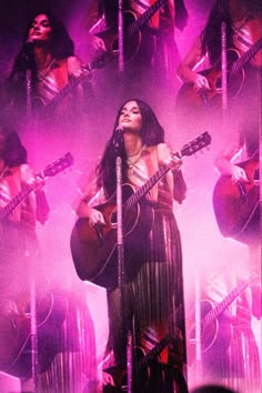 a woman singing into a microphone while holding a guitar