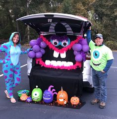 two people standing in front of a car decorated for halloween