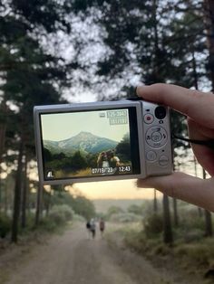 someone is holding up their camera to take a photo on the road in front of them