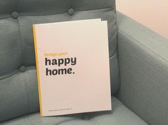 a book sitting on top of a gray couch next to a white and yellow sign